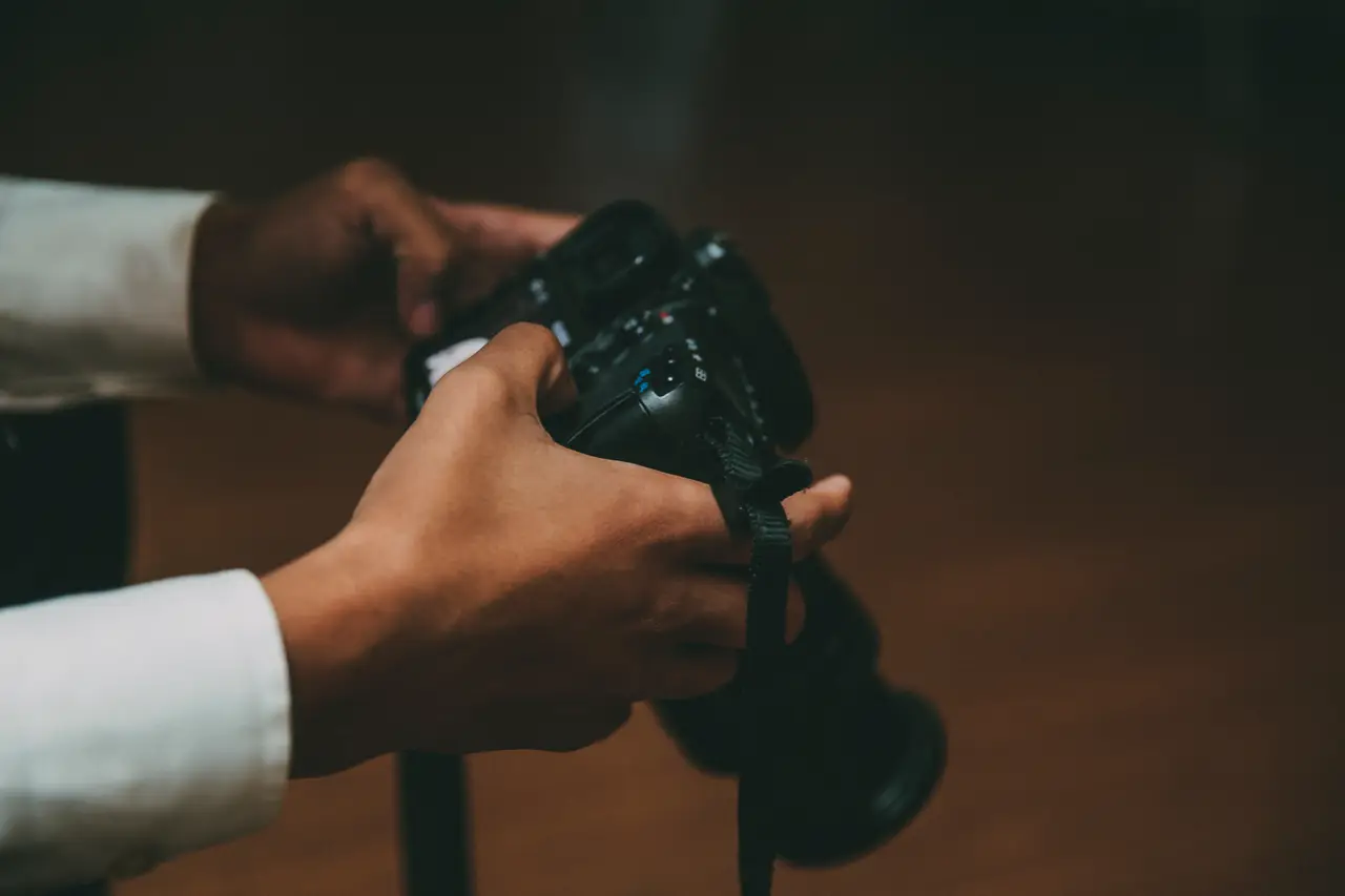 Hands holding a camera in low, warm light