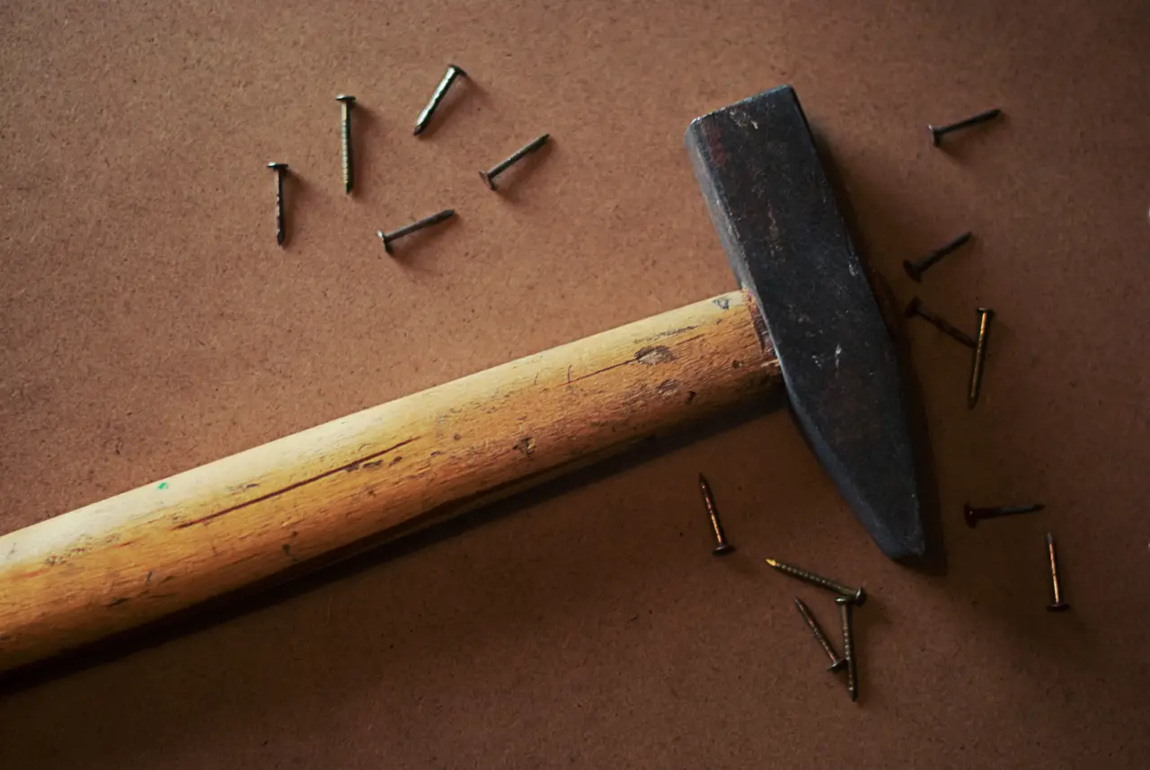 A hammer and scattered nails on a wooden board