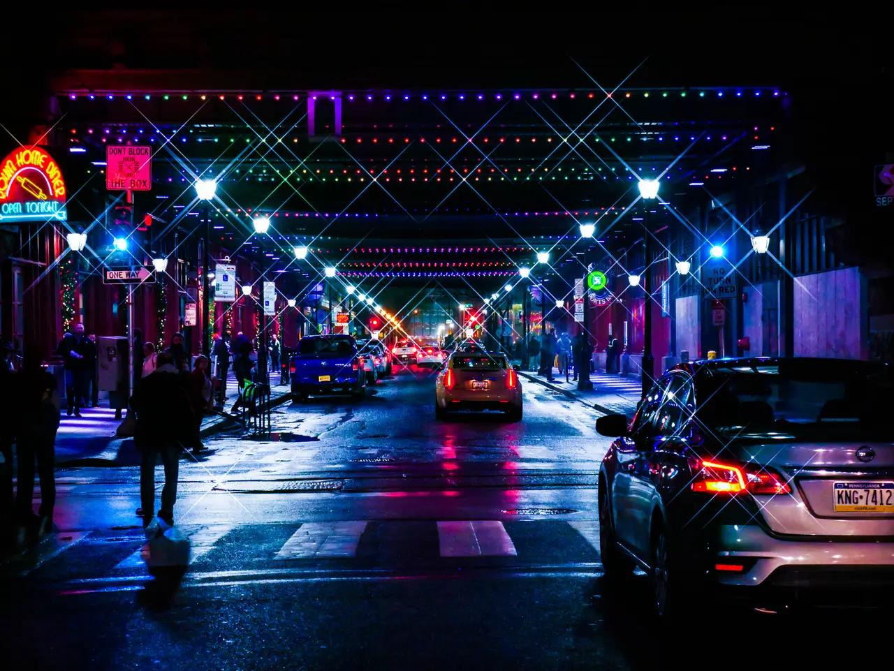 A rain-slick city street under neon lights at night